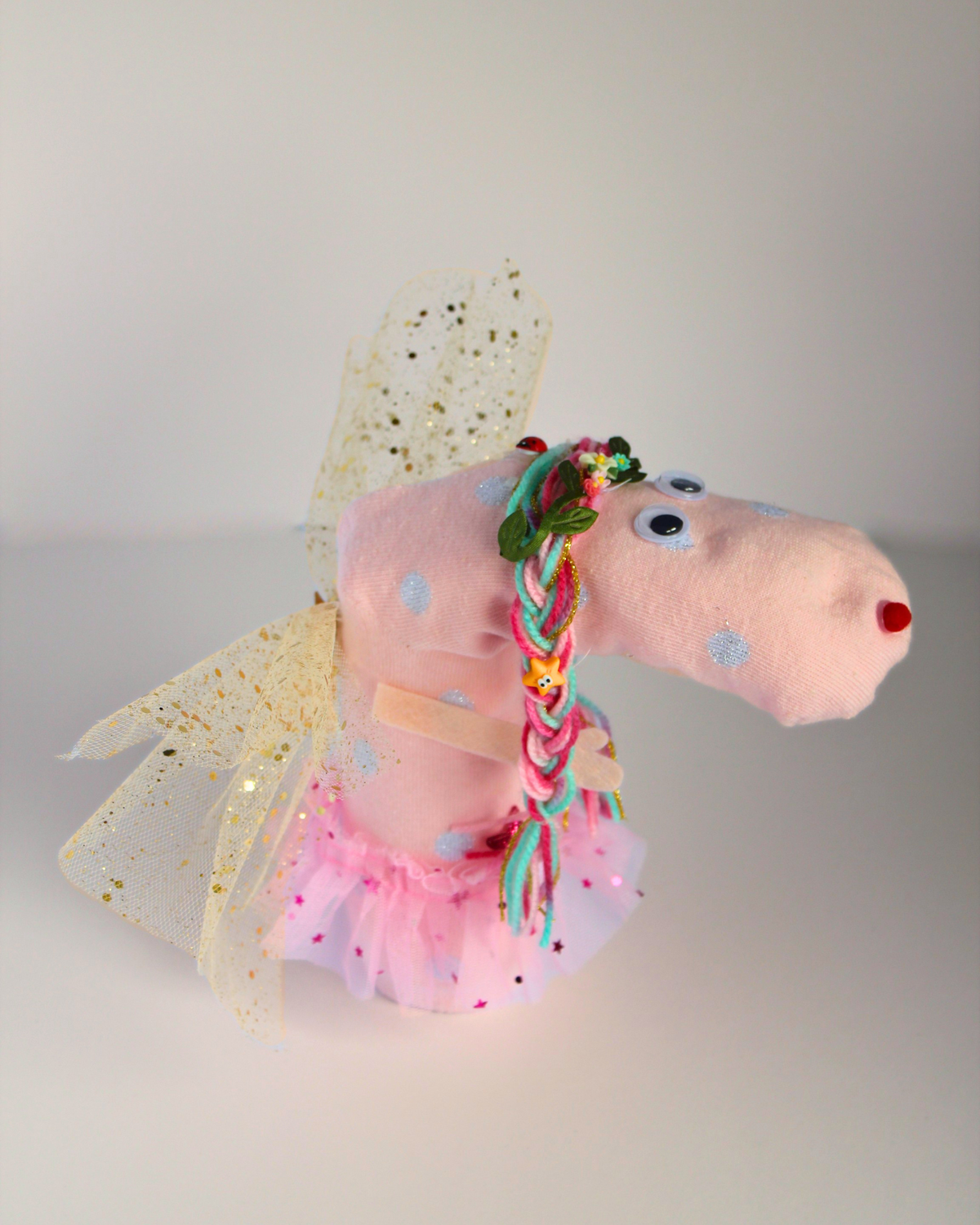 Side view of Cheeky the Fairy DIY sock puppet showing pink spotted sock, colourful wool hair, fairy wings and pink tutu