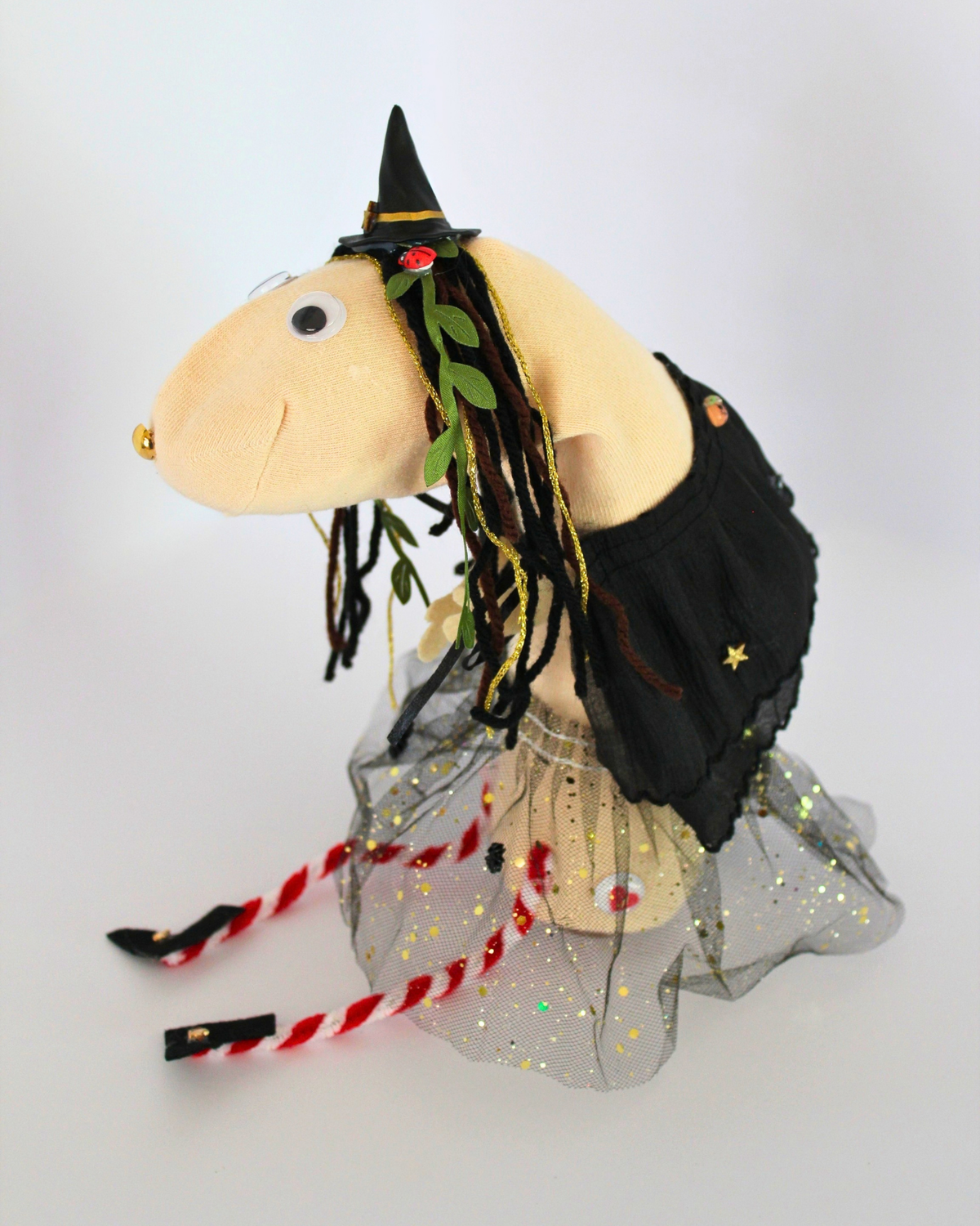 Side view of Punky witch sock puppet showing her black cape, wool hair, green vines and gold decorations